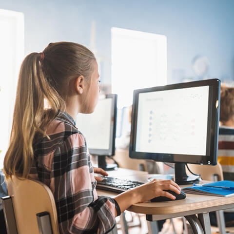 une élèves utilisant un ordinateur en salle de classe.
