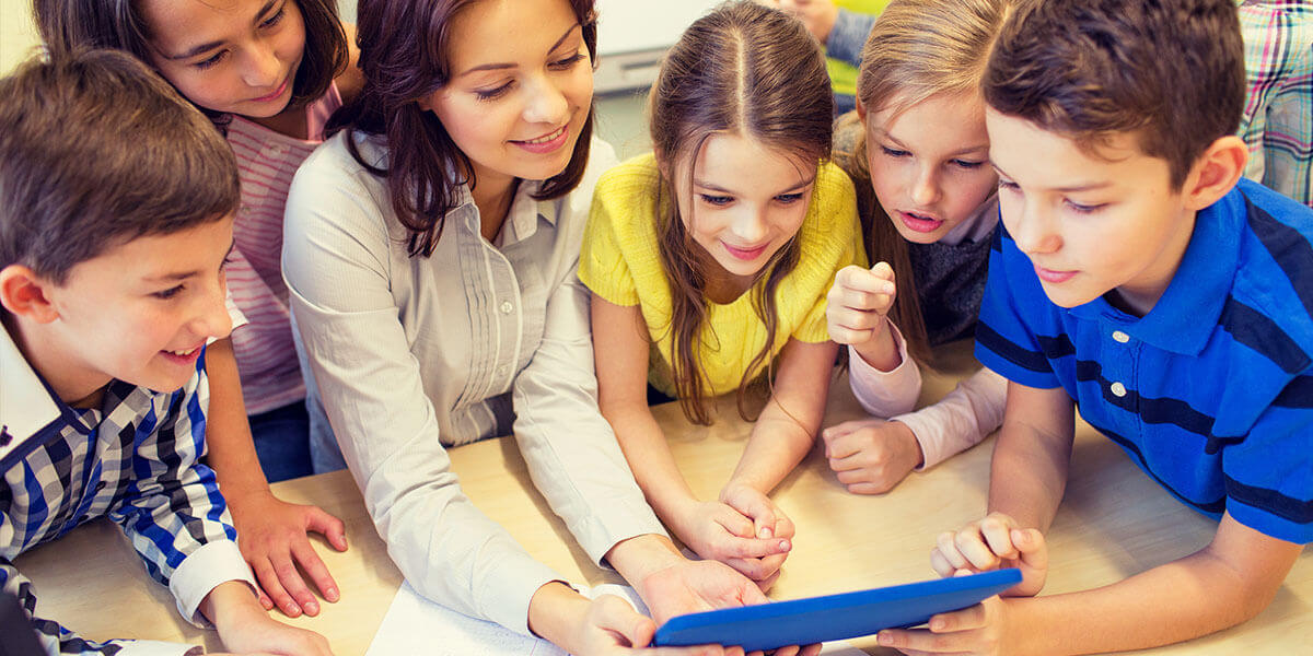 Groupes de jeunes avec une enseignante regardant une tablette électronique. 