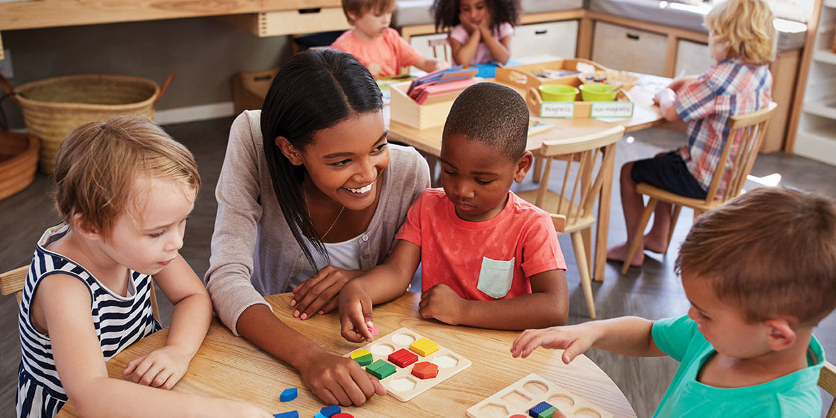 Enseignante utilisant des formes de bois avec des élèves de maternelle.