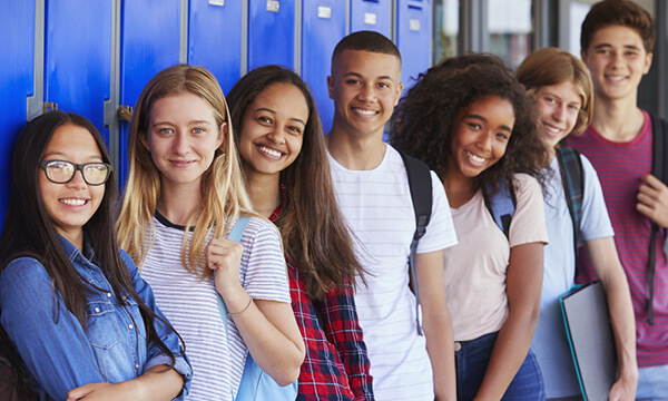Groups of smiling teenagers in a school hallway.