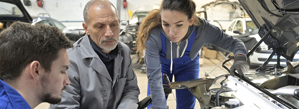 Instructor with students working on a car engine